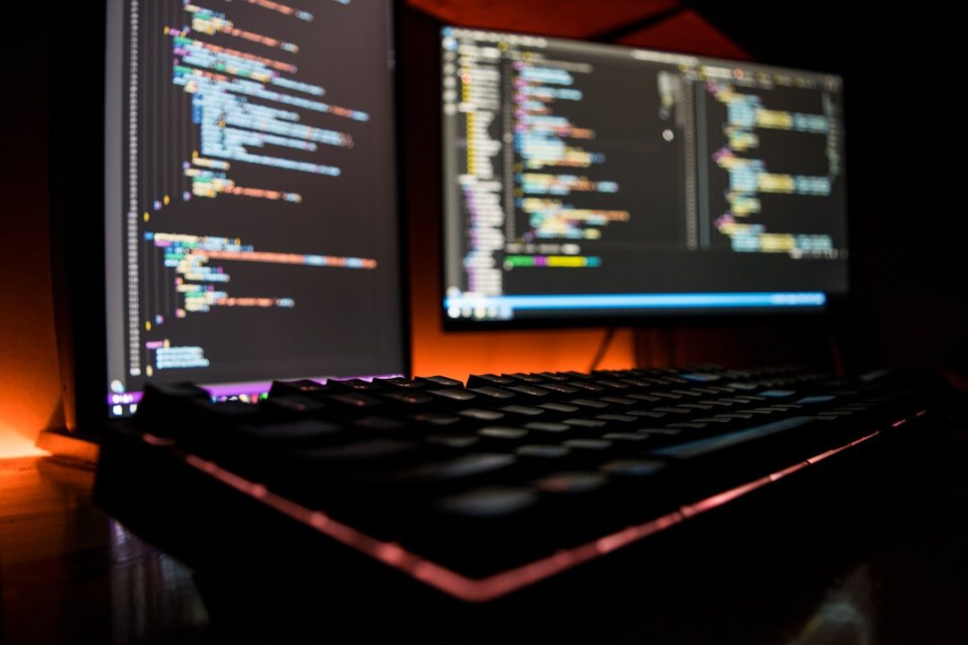 Software programming code on multiple computer screens in a dark developer environment